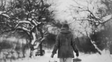 Zdjęcie kobiety idącej z wiadrami przez śnieg. Logo Przestrzeni Sztuki Katowice. Hasło: Laboratorium twórcze
